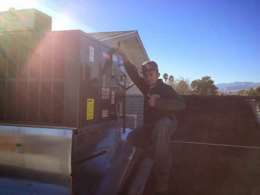 HVAC technician performing Air Duct Cleaning on a rooftop unit in Woodbridge